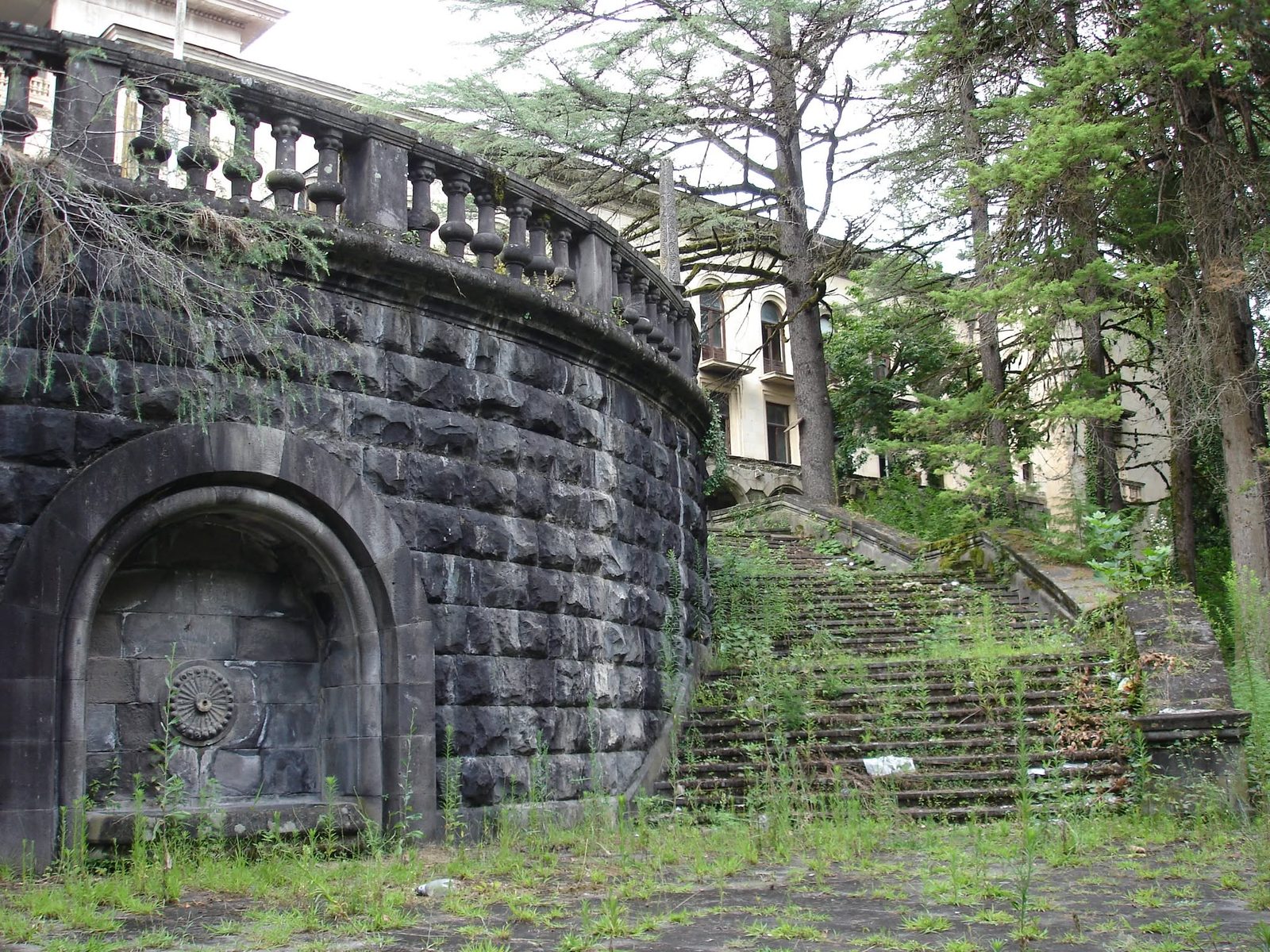 Eine Steinmauer mit Bogennische und Stufen nach oben.